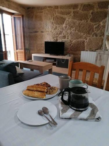 einen Tisch mit einem Teller Brot und einem Wasserkocher in der Unterkunft Casa de piedra céntrica. in Ribeira