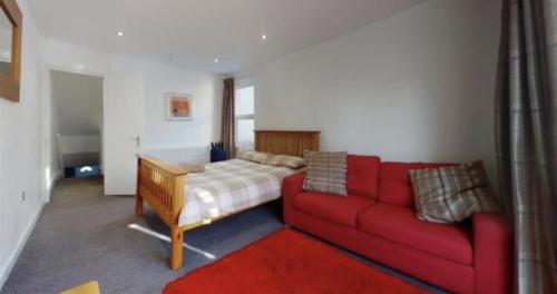 uma sala de estar com um sofá vermelho e uma cama em Myrtle villa 10 bedrooms sleeps 28, 2 min to beach em Melcombe Regis