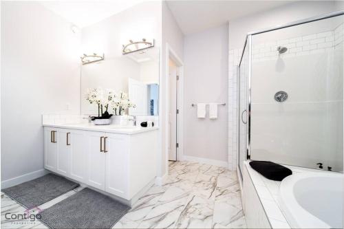 uma casa de banho branca com uma banheira e um lavatório em Boho Luxe Home, Sleeps 12, AirCon, King Bed, WiFi em Edmonton