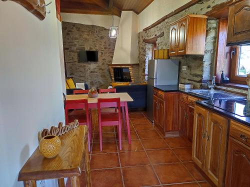 a kitchen with wooden cabinets and a table with chairs at Recanto da Encosta - T2 in Bragança