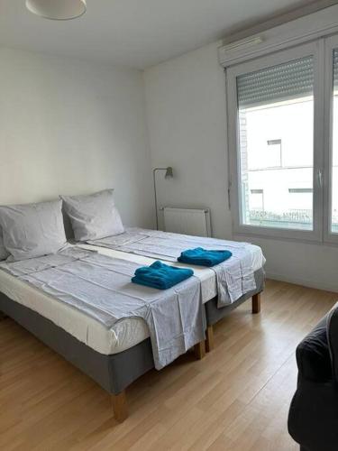 Un dormitorio con una cama con toallas azules. en Grand Studio de 37m carrés - Parking - RER Laplace et Maison des Examens à 5 minutes à pied en Arcueil