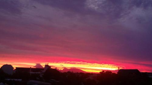 um pôr-do-sol com um céu vermelho e roxo em Régent 4e étage em Papeete