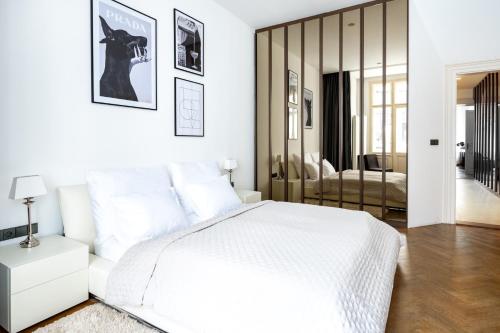 a white bedroom with a white bed and a mirror at Elegant Paris Ave apartment with a Terrace in Prague