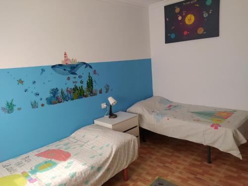 een kamer met 2 bedden en een blauwe muur bij A Balea Turquesa in Cangas de Morrazo