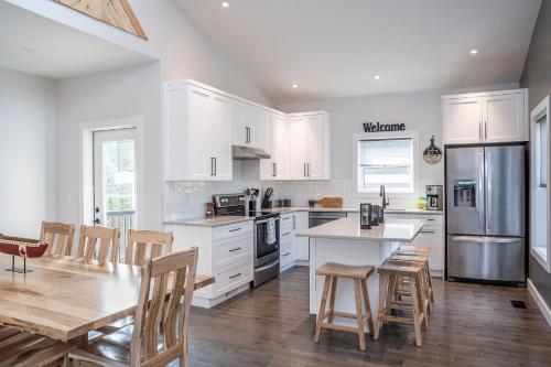 a kitchen with white cabinets and a table and chairs at Mountain Dreams - Revelstoke Home Near RMR in Revelstoke
