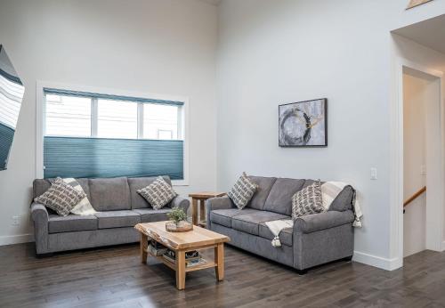 a living room with two couches and a table at Mountain Dreams - Revelstoke Home Near RMR in Revelstoke