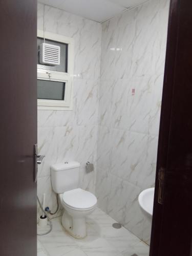 a white bathroom with a toilet and a sink at استوديو مفروش in Sharjah