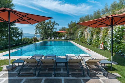 einen Pool mit Stühlen, Tischen und Sonnenschirmen in der Unterkunft Luxury Pool Villa Oliveto in Ciciana