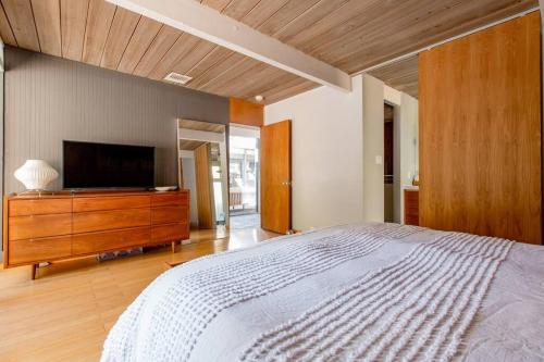a bedroom with a large bed and a flat screen tv at Eichler Mid Century Modern Designer Pool/Jacuzzi in Thousand Oaks