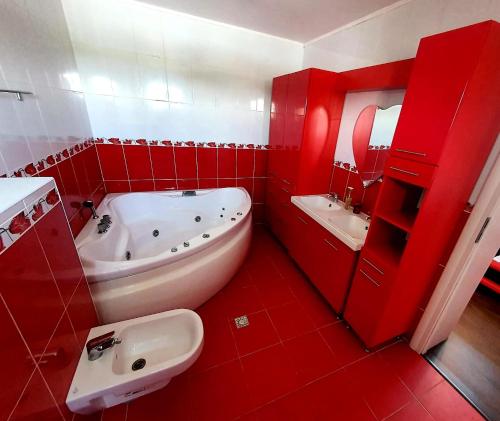ein rotes Badezimmer mit einer Badewanne und einem Waschbecken in der Unterkunft Alpha Pool House in Ghionea