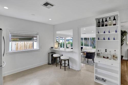 a kitchen with white walls and a bar with stools at Swinton Stay in Delray Beach