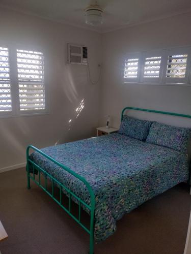 een slaapkamer met een bed in een kamer met ramen bij Ocean Breeze Apartments in Hervey Bay