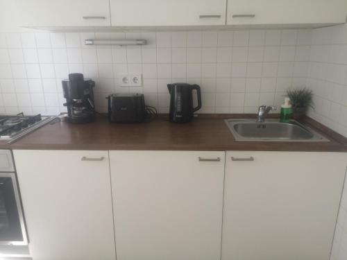 eine Küche mit weißen Schränken und einem Waschbecken in der Unterkunft Antik Apartman in Veszprém