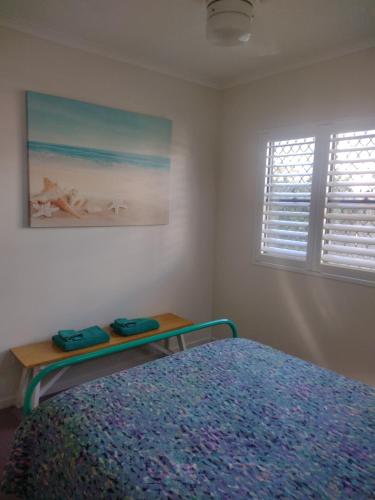 a bedroom with a bed and a table next to a window at Ocean Breeze Apartments in Hervey Bay