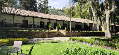 a building with a patio and a yard with chairs at Hacienda Suescún - 300 Años de Historia in Tibasosa