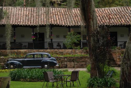 an old car parked in front of a house at Hacienda Suescún - 300 Años de Historia in Tibasosa