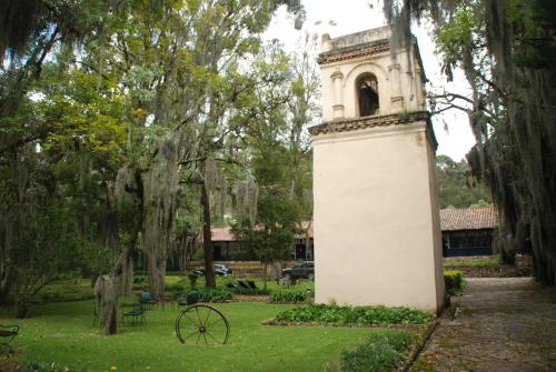 a tower in the middle of a park with trees at Hacienda Suescún - 300 Años de Historia in Tibasosa