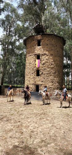 a group of people riding horses in front of a tower at Hacienda Suescún - 300 Años de Historia in Tibasosa