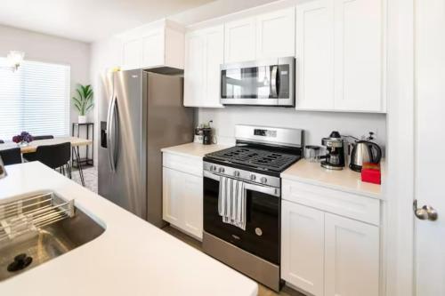 a kitchen with white cabinets and a black stove top oven at NEW 4-bed 4-bath Stylish House with Mountain View and 2 garages in Lehi