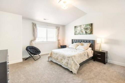 a bedroom with a bed and a chair and a window at NEW 4-bed 4-bath Stylish House with Mountain View and 2 garages in Lehi