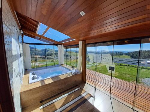 a large bathroom with a tub with a large window at Chalés Conforto Mineiro in Gonçalves