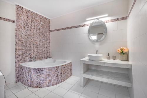 a bathroom with a tub and a sink and a mirror at Nikolas Old Town in Rhodes Town