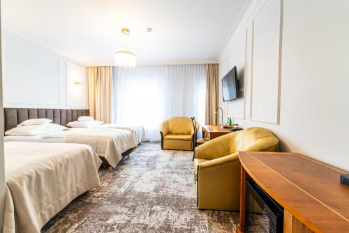 Habitación de hotel con 2 camas y 2 sillas en Hotel Piast, en Opole