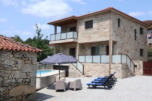 a house with a swimming pool and an umbrella and chairs at Casa do Moinho in Cabeceiras de Basto