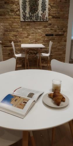 a book on a table with a plate of food on it at B&B Dimora Damiani in Montefiore dellʼAso