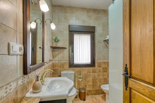 łazienka z umywalką, toaletą i lustrem w obiekcie Apartamentos rurales Alameda del Jerte w mieście El Torno