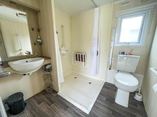 a bathroom with a toilet and a sink and a mirror at Lovely Wheelchair Friendly Caravan At Skipsea Sands In Yorkshire Ref 41167wf in Barmston