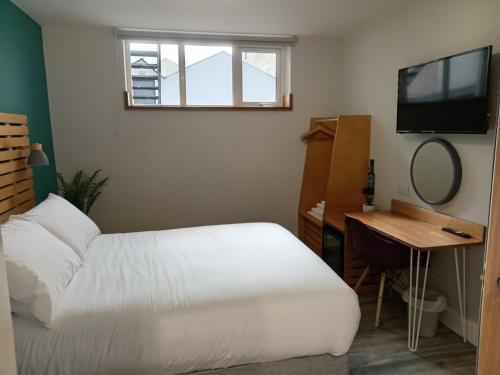 a bedroom with a bed and a desk with a mirror at No.5 in Derry Londonderry