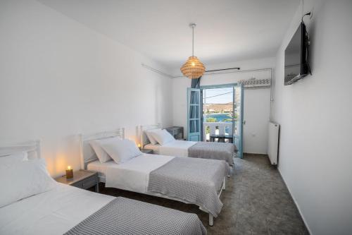 a hotel room with three beds and a television at Eleios Hotel Serifos in Livadi