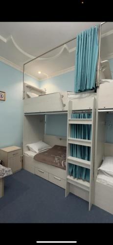 a room with two bunk beds with blue curtains at LOONA FAMILY HOSTEL in Tashkent