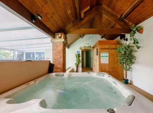 una grande vasca da bagno in una camera con soffitti in legno di Goldfinch cottage a Newton