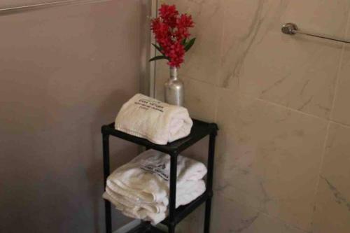 un baño con un estante con toallas y un jarrón de flores en Casa Machupicchu - Huayllabamba, Urubamba Cusco, Perú, 