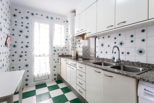 una cocina con armarios blancos y suelo de color blanco y verde a cuadros. en Vacaciones Canet Playa - en primera linea en Canet de Berenguer