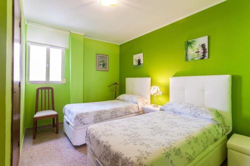 ein grünes Schlafzimmer mit 2 Betten und einem Stuhl in der Unterkunft Vacaciones Canet Playa - en primera linea in Canet d'en Berenguer