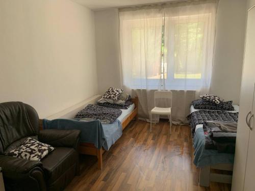 a room with three beds and a couch and a window at 2 Zimmer Wohnung 1min Messe Köln in Cologne