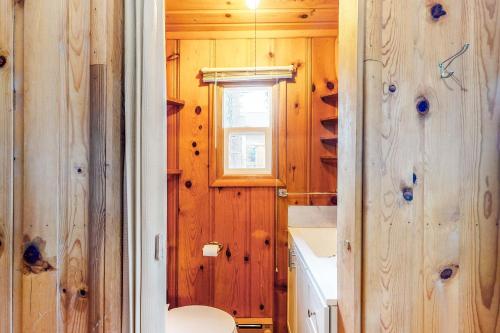 uma casa de banho com paredes de madeira, um WC e uma janela em Loon Lake Retreat em Loon Lake