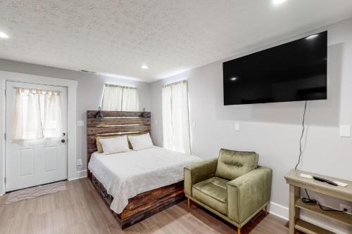 1 dormitorio con 1 cama, 1 silla y TV en Greenwood Getaway Apartment en Greenwood