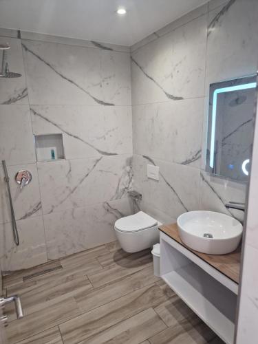 a bathroom with a toilet and a sink and a shower at Joanna Suites in Sarandë
