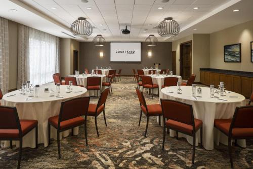a conference room with tables and chairs and a screen at Courtyard by Marriott Santa Barbara Goleta in Santa Barbara