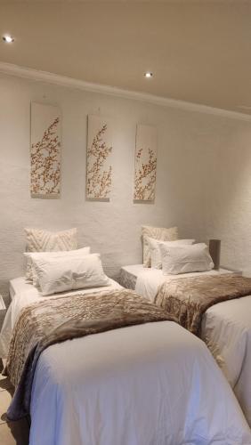 two beds in a room with paintings on the wall at Rest&Relax Guesthouse in Johannesburg