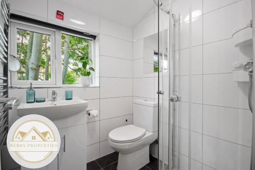 Baño blanco con aseo y lavamanos en 2 Bed home-Sleeps 5-near station & great location, en Londres