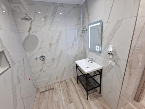 a white bathroom with a sink and a shower at Joanna Suites in Sarandë