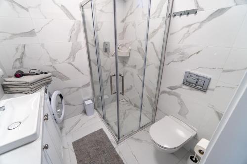 a white bathroom with a shower and a toilet at Memory Dębki in Dębki