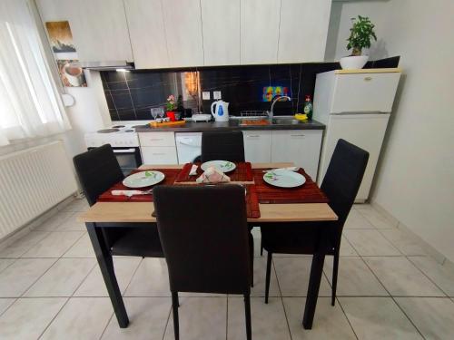 a kitchen with a wooden table with chairs and a white refrigerator at Antonia's cozy apartment in Agia Triada