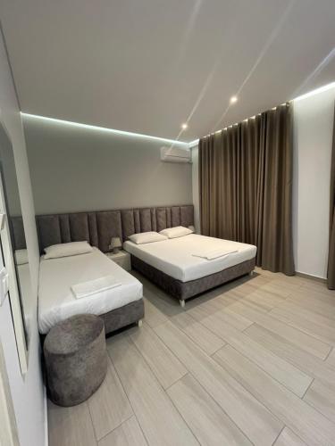 a room with two beds and a ottoman in it at Hotel LIDI in Sarandë