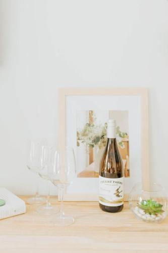 a bottle of wine sitting on a table with wine glasses at Naramata Courtyard Suites in Naramata